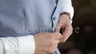 英俊时尚的男人穿着现代正式的衣服扣扣子夹克。 把穿蓝色夹克，白色衣服的家伙的手举起来